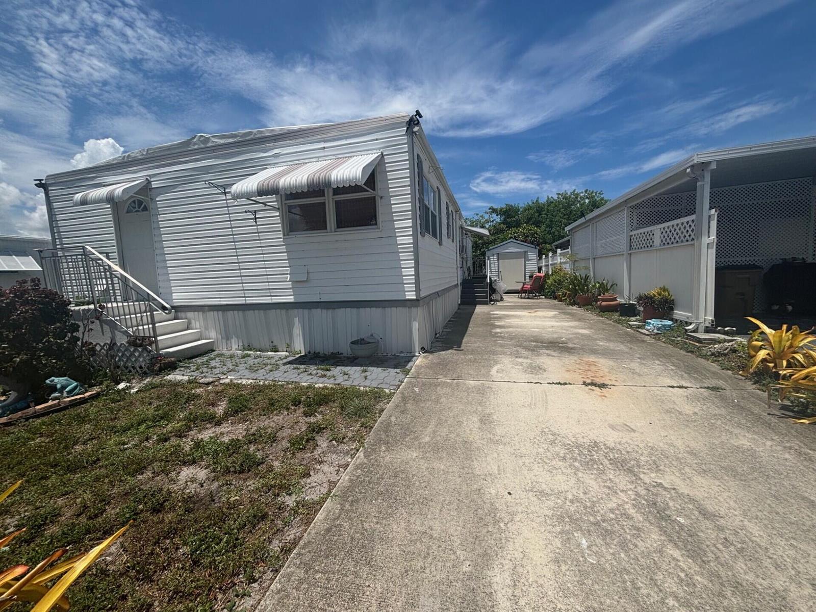 A white mobile home with a concrete driveway and a small storage shed in back — 109 NW 50th Street, Deerfield Beach FL 33064, DEERFIELD BEACH, FL