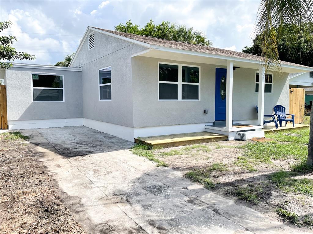 A single-story house with light gray stucco siding, a blue front door, and a concrete driveway — 4537 10TH AVENUE S, ST PETERSBURG, FL