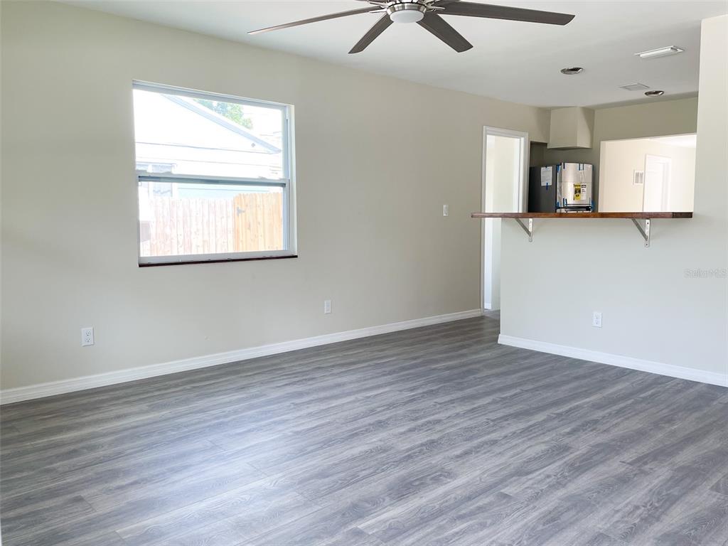 An interior view shows a living area with gray wood-look flooring and a breakfast bar — 4537 10TH AVENUE S, ST PETERSBURG, FL
