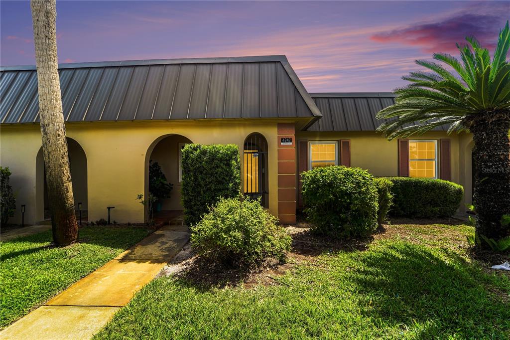 A single-story house with a metal roof, arched entryways, and a landscaped front yard — 4247 STRATFORD DRIVE, NEW PORT RICHEY, FL
