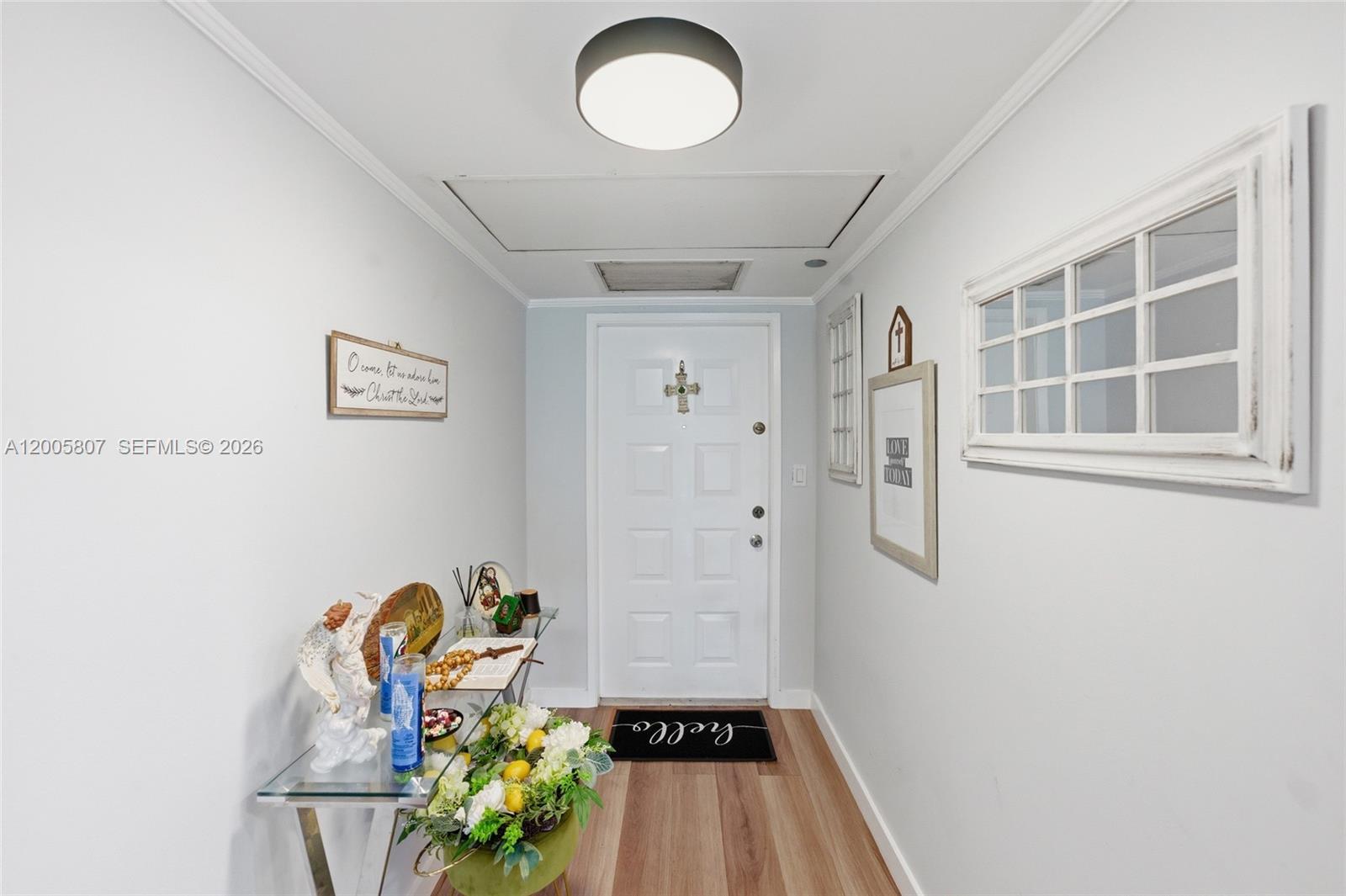 A bright entryway features a white door, light wood flooring, and a glass console table — 625 Oaks Dr # 304, Pompano Beach FL 33069, POMPANO BEACH, FL