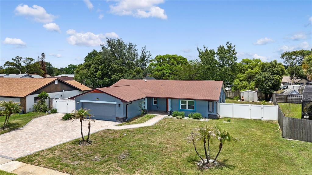 An aerial view shows a blue single-story house with a paved driveway and fenced yard — 1055 PALOS VERDE DRIVE, ORLANDO, FL