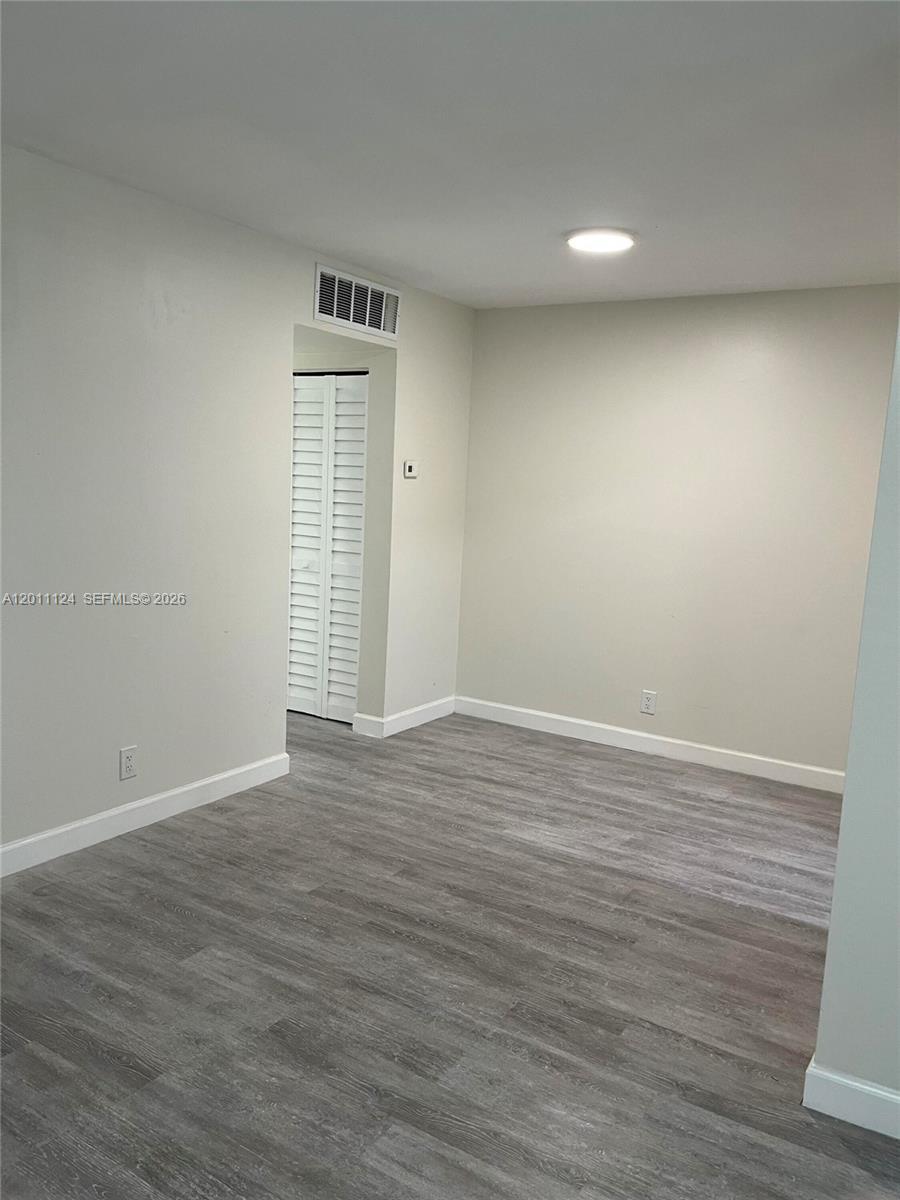 A room with light-colored walls, gray wood-look flooring, and a white louvered closet door — 2134 Lincoln St # 18, Hollywood FL 33020, HOLLYWOOD, FL