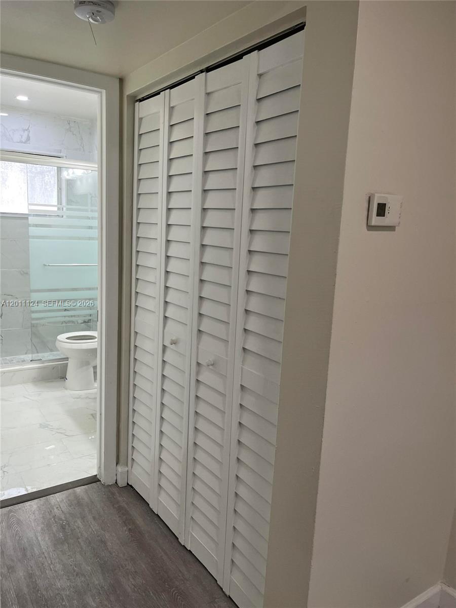 A white louvered closet door stands next to a doorway leading into a tiled bathroom — 2134 Lincoln St # 18, Hollywood FL 33020, HOLLYWOOD, FL