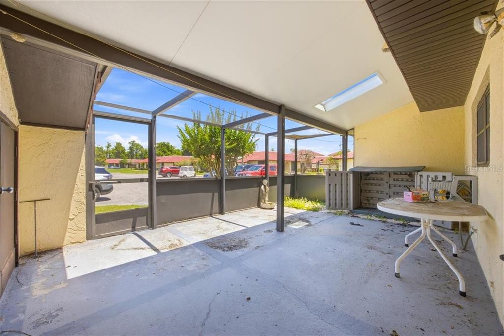 A covered patio with a screened enclosure, concrete flooring, and a small white table — 535 HUNTER CIRCLE UNIT 535, KISSIMMEE, FL