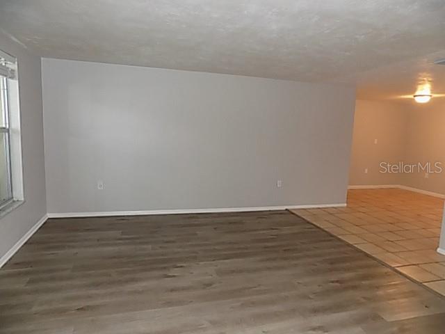 A room with gray walls, wood-look flooring, and an adjacent tiled area — 2173 FIESTA DRIVE, SARASOTA, FL