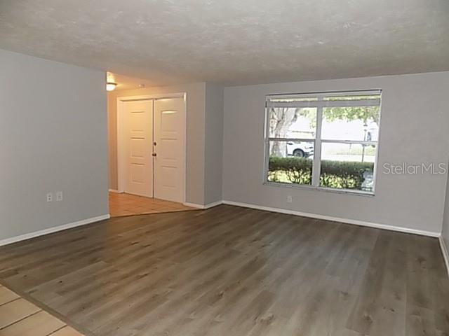 An empty living room with light gray walls, wood-look flooring, and a large window — 2173 FIESTA DRIVE, SARASOTA, FL