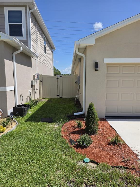 The exterior side yard features a grassy area, a vinyl gate, and a landscaped bed — 559 WAYLAND DRIVE, HAINES CITY, FL