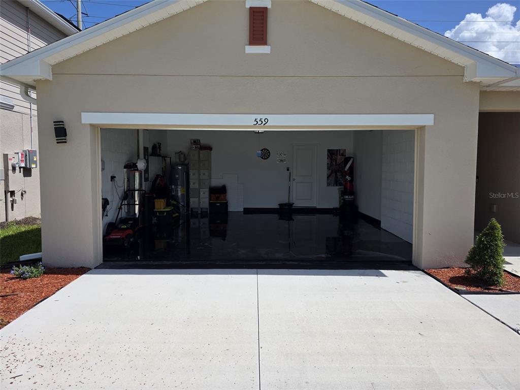 A view of a garage with a dark epoxy floor and a concrete driveway — 559 WAYLAND DRIVE, HAINES CITY, FL