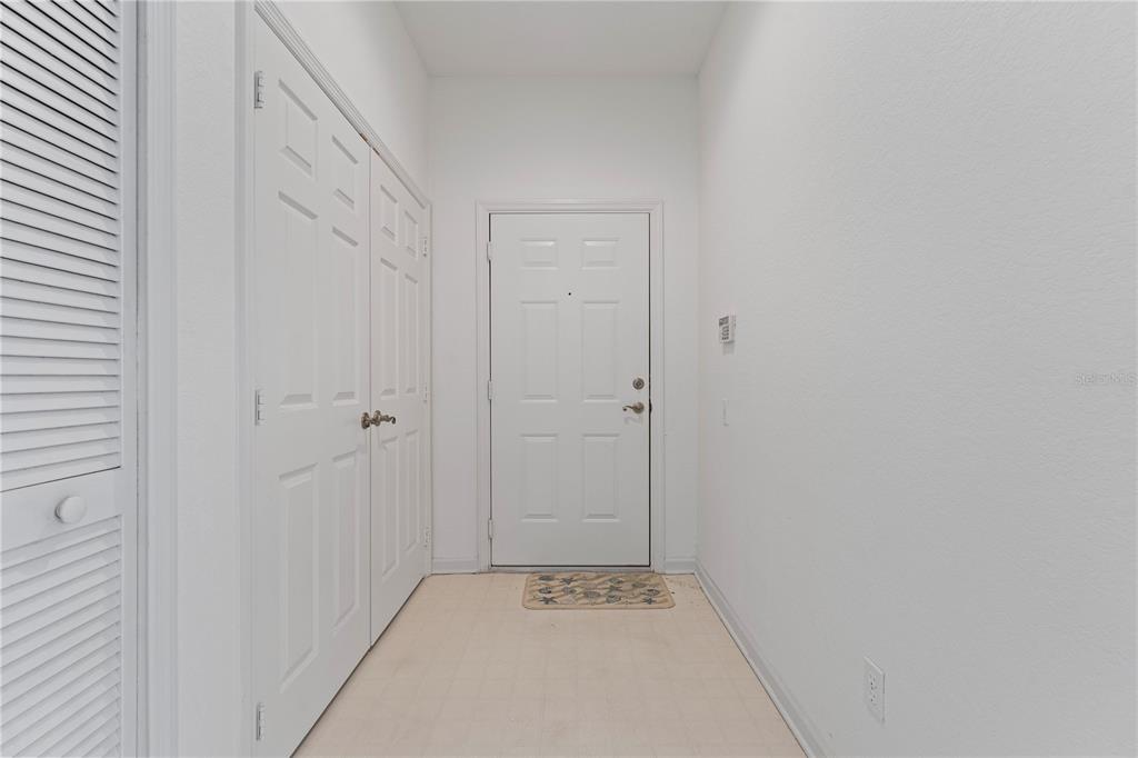 A white entryway features a front door, a louvered closet door, and tile flooring — 1212 S HIAWASSEE ROAD UNIT 525, ORLANDO, FL