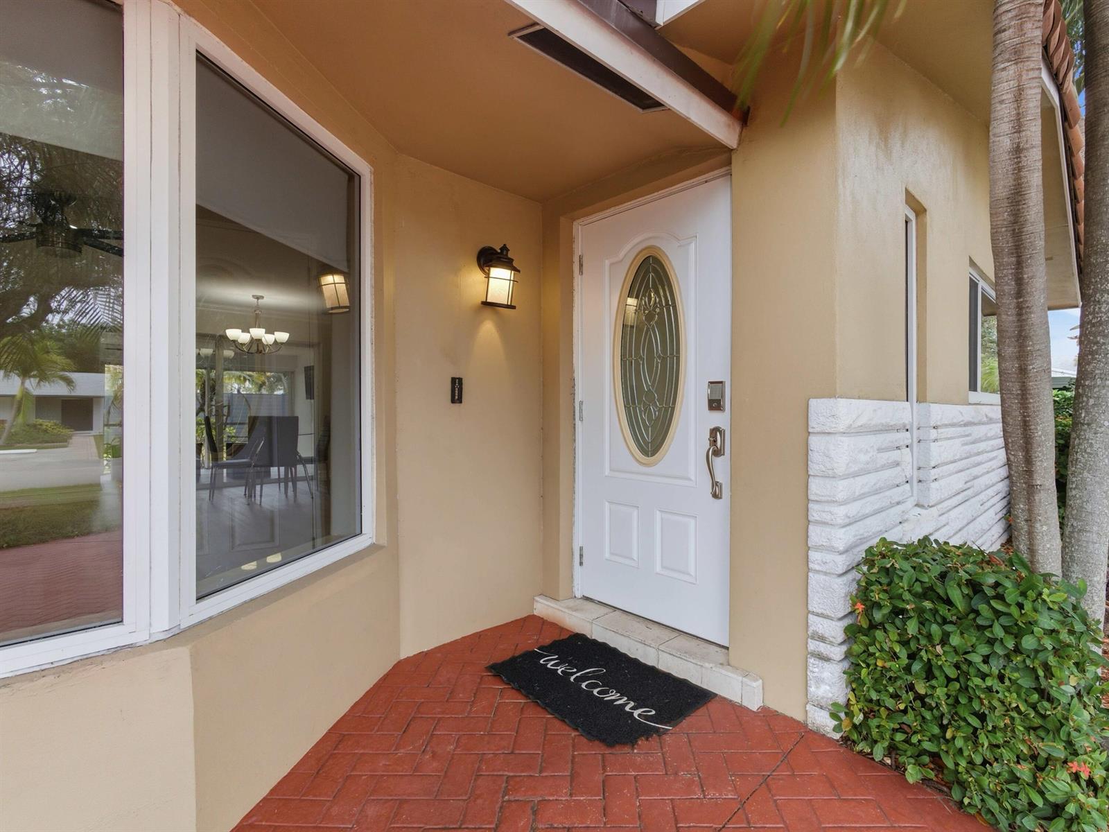 A white front door with an oval glass insert sits on a red brick porch — 1921 NE 28th Court, Lighthouse Point FL 33064, LIGHTHOUSE POINT, FL