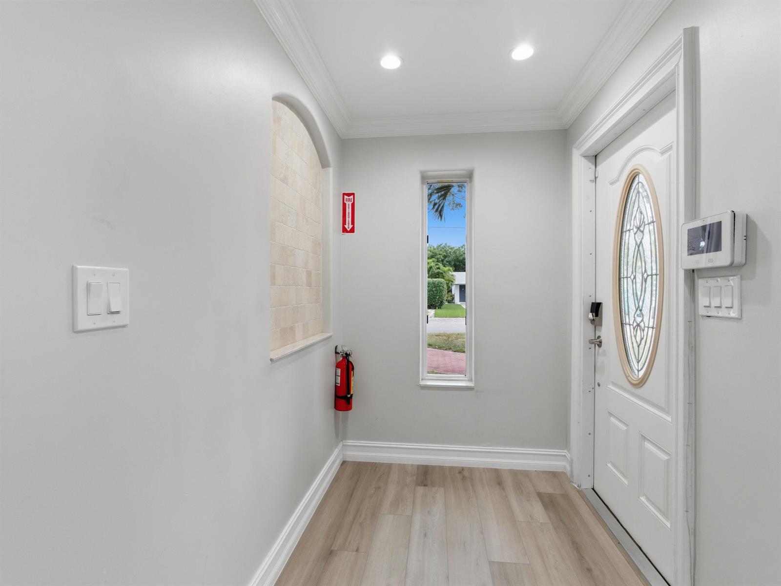 An entryway features light wood flooring, a white door with a glass insert, and a niche — 1921 NE 28th Court, Lighthouse Point FL 33064, LIGHTHOUSE POINT, FL