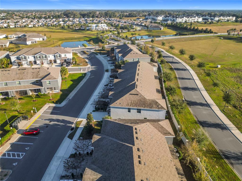 An aerial view shows multi-story townhomes with brown roofs, parking lots, and surrounding suburban landscaping — 5391 DRAGONFLY DRIVE, WILDWOOD, FL