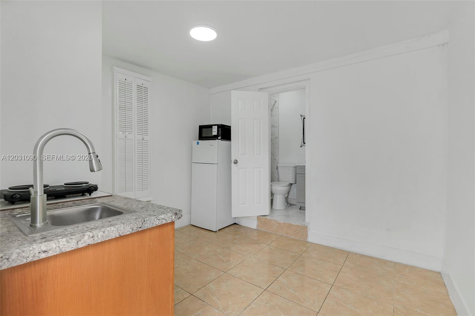 A small kitchen area features a sink, a mini-fridge, and an adjacent bathroom doorway — 6101 SW 24th St # 4, Miramar FL 33023, MIRAMAR, FL