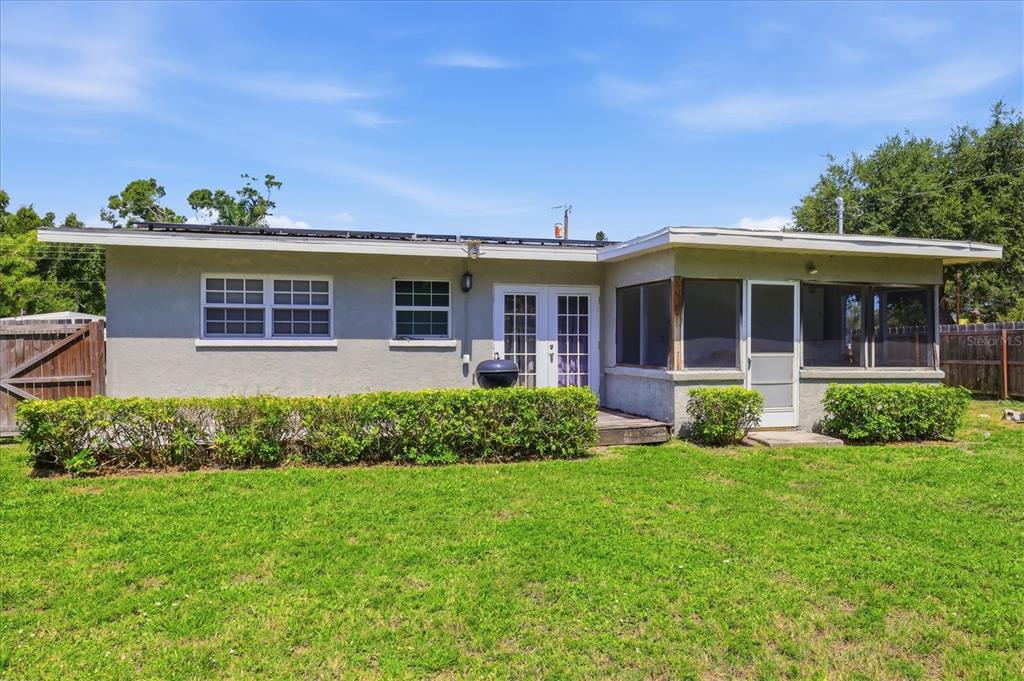 The exterior of a single-story house features a screened-in porch and a grassy backyard — 910 16TH AVENUE W, PALMETTO, FL