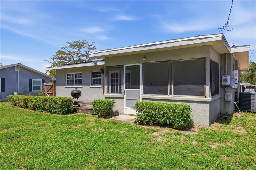 A single-story house with a screened-in porch, a small wooden deck, and a grassy yard — 910 16TH AVENUE W, PALMETTO, FL