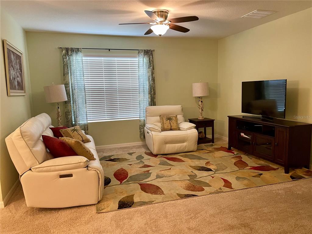 A living room features a white sofa, a matching armchair, and a television on a stand — 119 FISHERMANS COVE DRIVE, EDGEWATER, FL