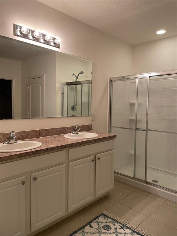 A bathroom features a double vanity with a speckled countertop and a glass-enclosed shower — 119 FISHERMANS COVE DRIVE, EDGEWATER, FL