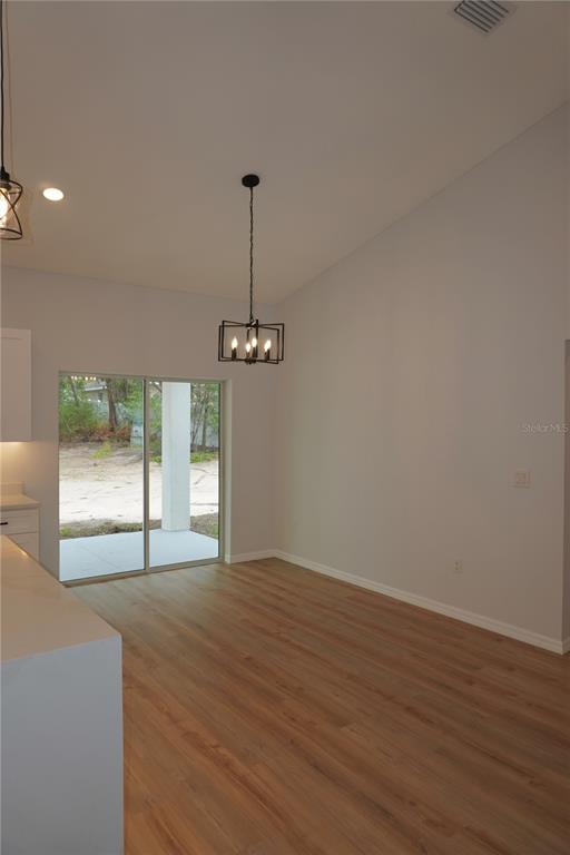 A dining area features light wood-look flooring, a vaulted ceiling, and a sliding glass door — 16 HEMLOCK TRL, OCALA, FL