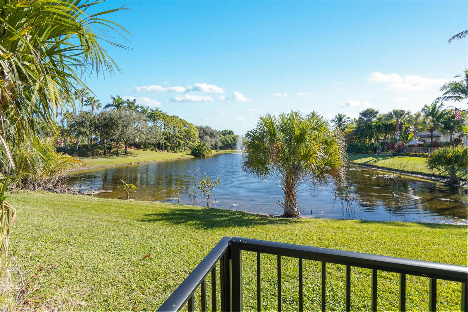 A view of a pond with a fountain, surrounded by palm trees and green grass — 19434 Estuary Drive, Boca Raton FL 33498, BOCA RATON, FL