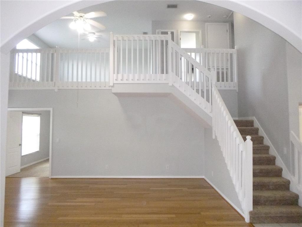A living room features hardwood floors, a carpeted staircase, and a white wooden railing loft — 19146 CYPRESS GREEN DRIVE, LUTZ, FL