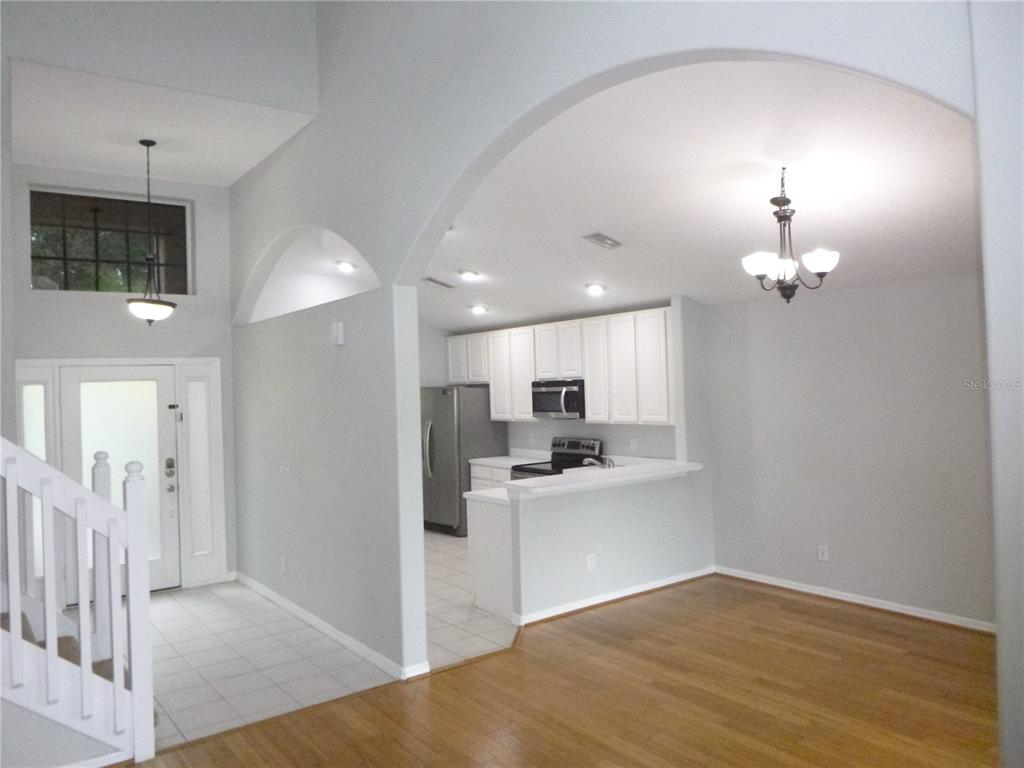 An open-concept kitchen with white cabinets and a breakfast bar overlooks a hardwood living area — 19146 CYPRESS GREEN DRIVE, LUTZ, FL