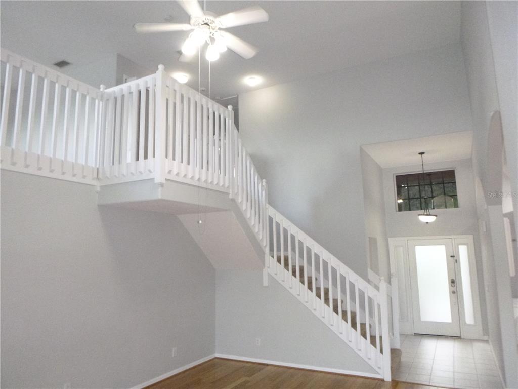 A bright foyer features a white staircase with a landing and a ceiling fan above — 19146 CYPRESS GREEN DRIVE, LUTZ, FL