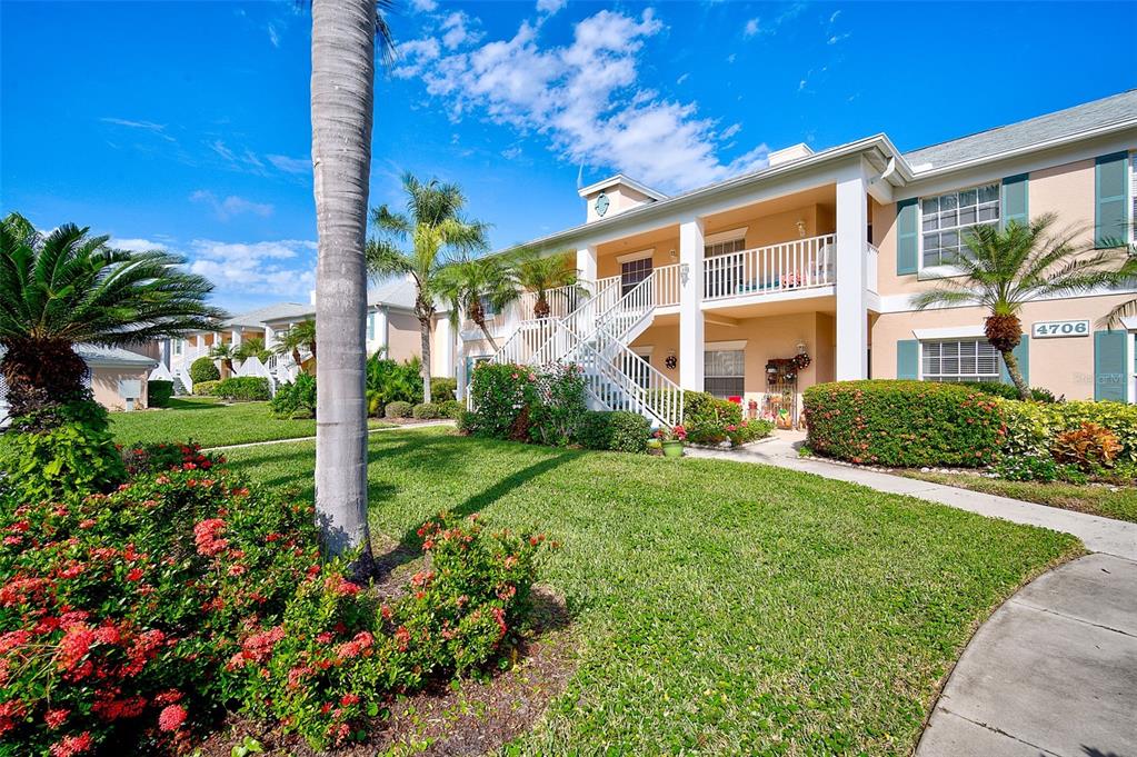 A two-story apartment building with a white staircase and a landscaped front yard — 4706 SAND TRAP STREET CIRCLE E UNIT 202, BRADENTON, FL