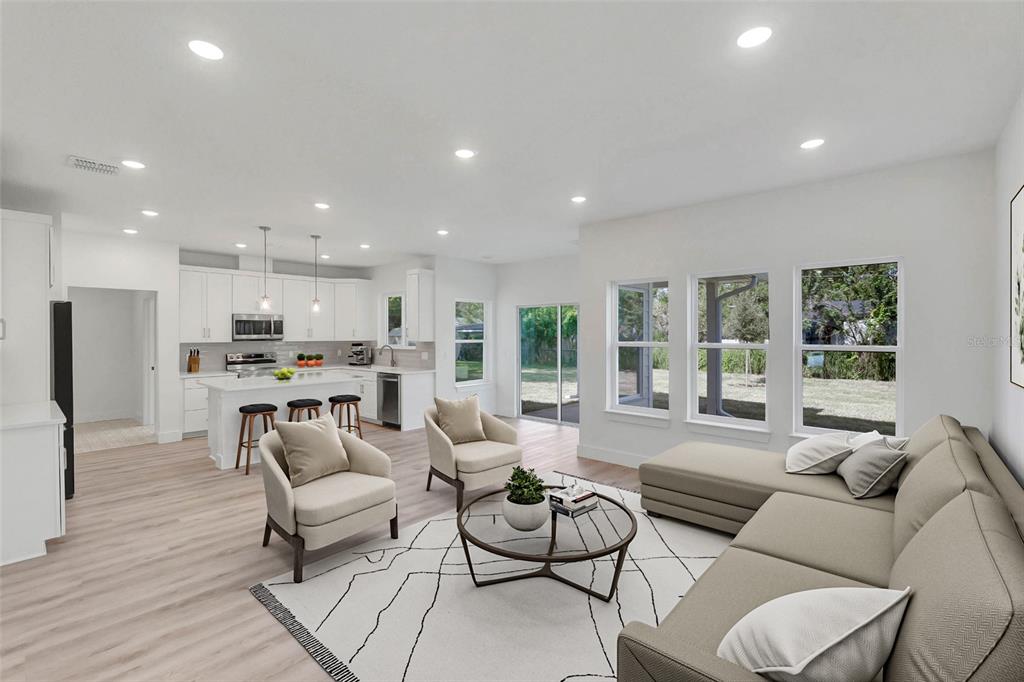 An open-concept living room and kitchen with light wood floors, neutral furniture, and large windows — Lot #21 KAROLINA AVE, WINTER PARK, FL
