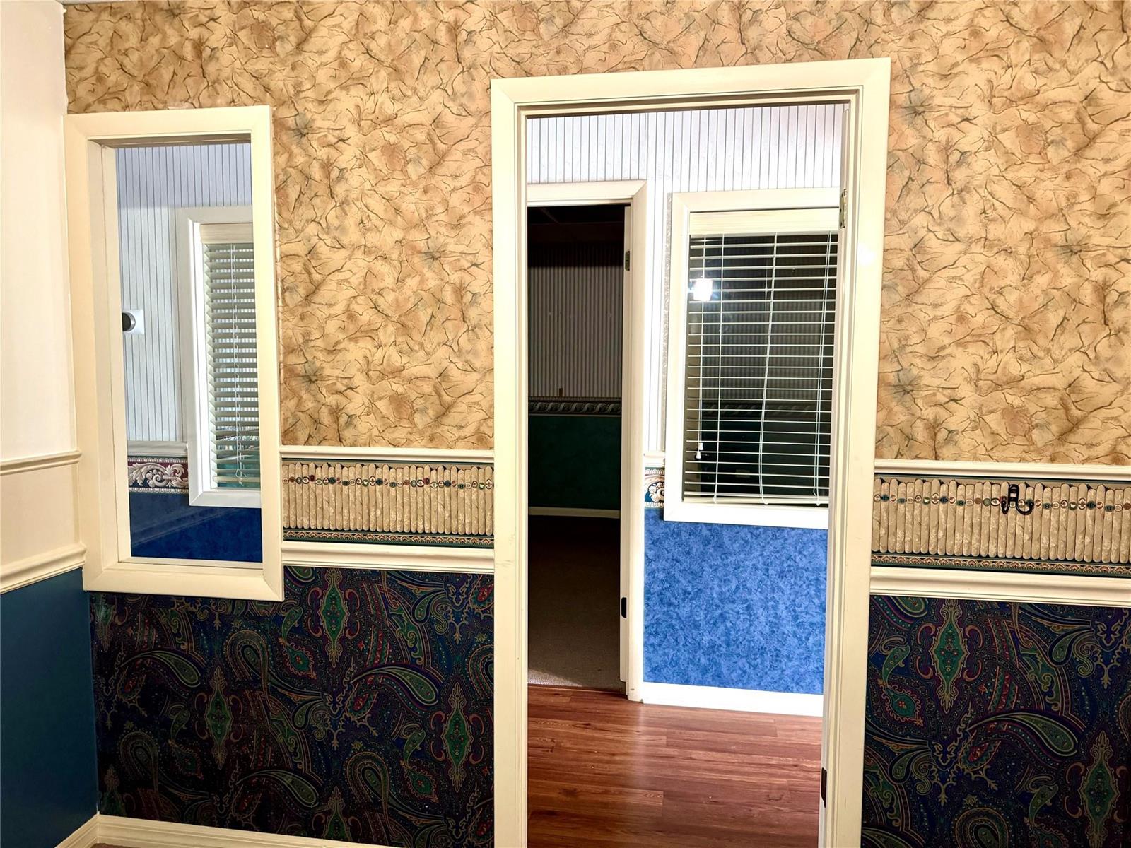 A hallway features walls with patterned wallpaper, blue paisley wainscoting, and a central doorway — 145 S Ridgewood Drive, Sebring FL 33870, SEBRING, FL