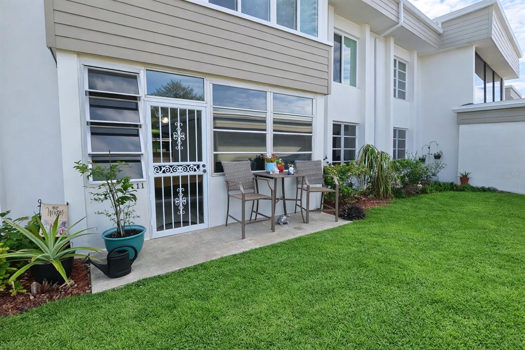 A ground-level patio with a table and chairs sits outside a white building entrance — 21300 BRINSON AVENUE UNIT 111, PORT CHARLOTTE, FL