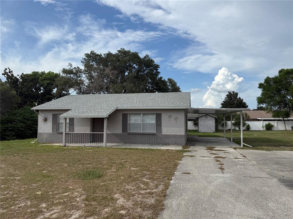 A single-story house with a gray exterior, brick base, and an attached carport — 12131 ROCKFORD STREET, SPRING HILL, FL