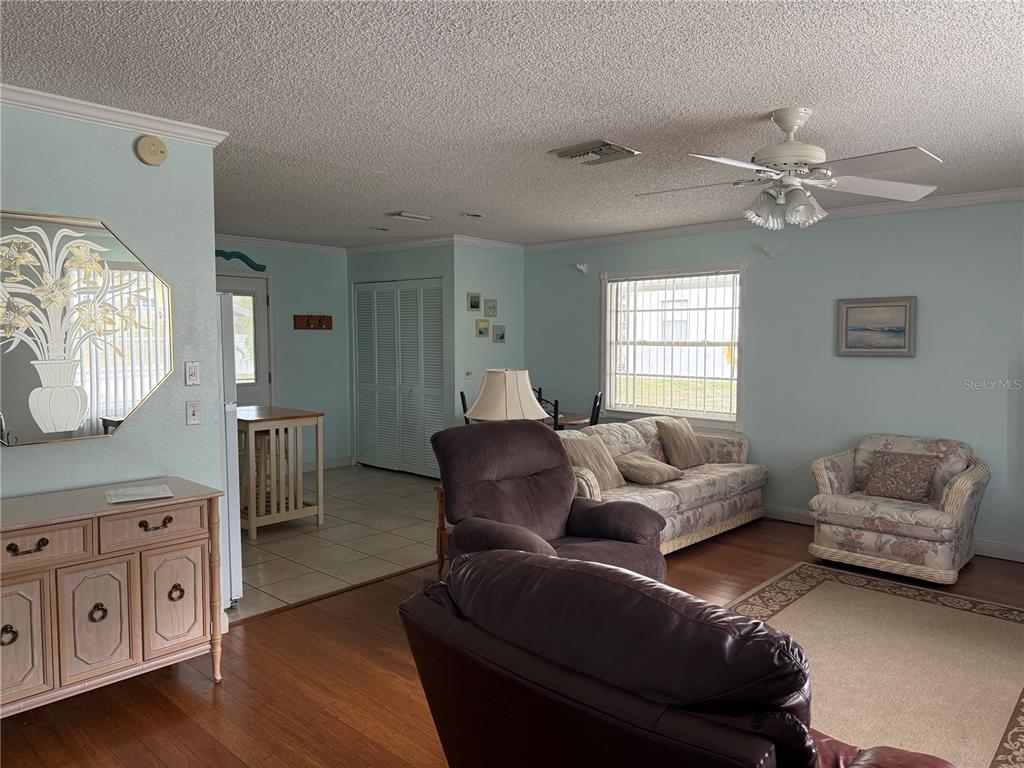 A living room features light blue walls, wood flooring, a ceiling fan, and traditional furniture — 12131 ROCKFORD STREET, SPRING HILL, FL