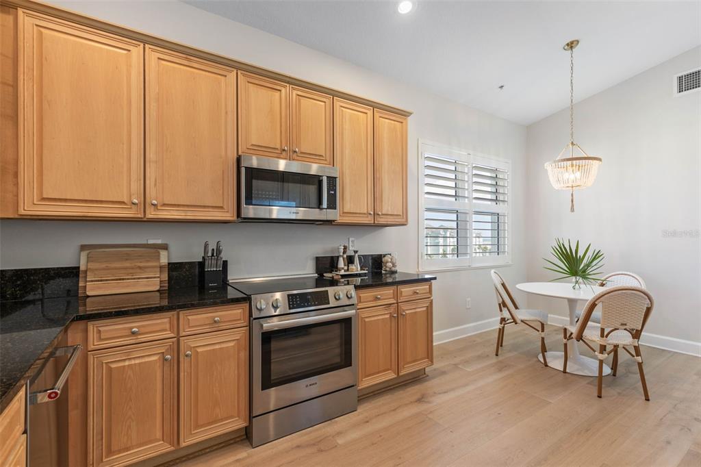 A dining area and living room with light wood floors overlook a balcony and ocean — 400 CINNAMON BEACH WAY UNIT 365, PALM COAST, FL
