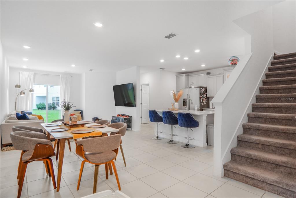 An open-concept living and dining area features tile floors, a kitchen island, and carpeted stairs — 3510 BEAU ROAD, KISSIMMEE, FL