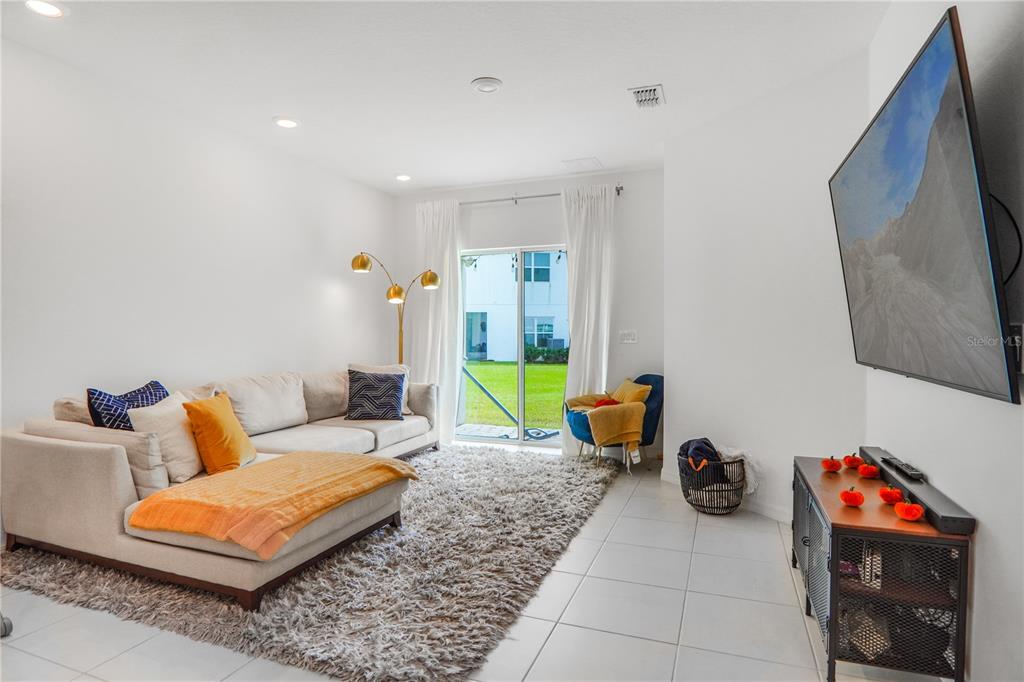 A living room features a sectional sofa, a shag rug, and a wall-mounted television — 3510 BEAU ROAD, KISSIMMEE, FL
