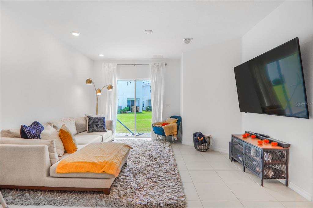 A living room features a sectional sofa, a large television, and a sliding glass door — 3510 BEAU ROAD, KISSIMMEE, FL