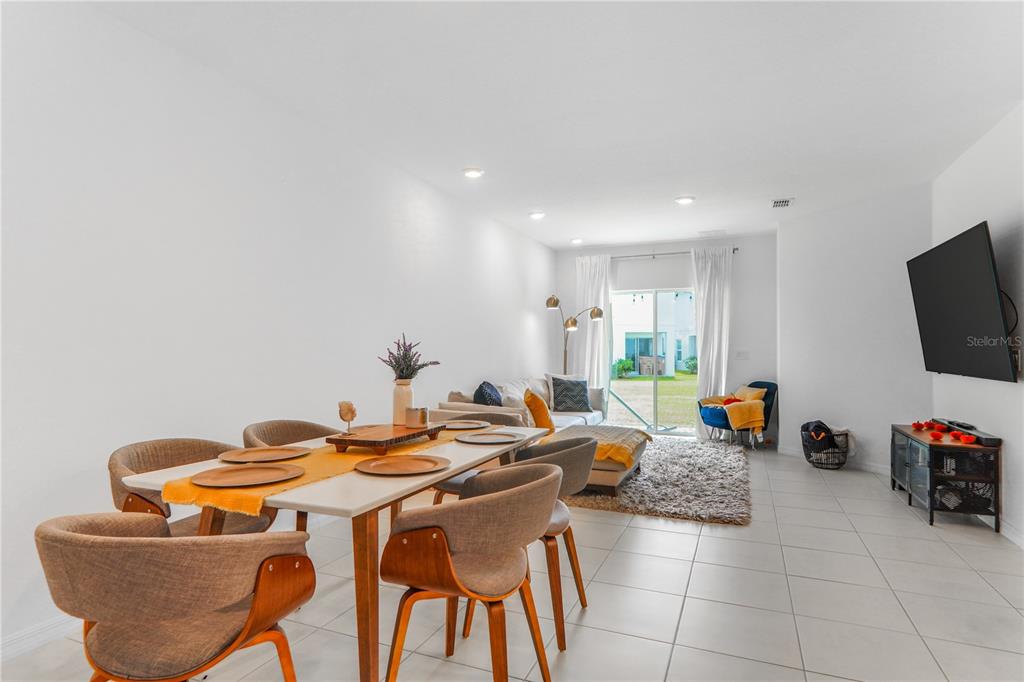 A bright, open-concept living and dining area features white tile floors and a sliding glass door — 3510 BEAU ROAD, KISSIMMEE, FL