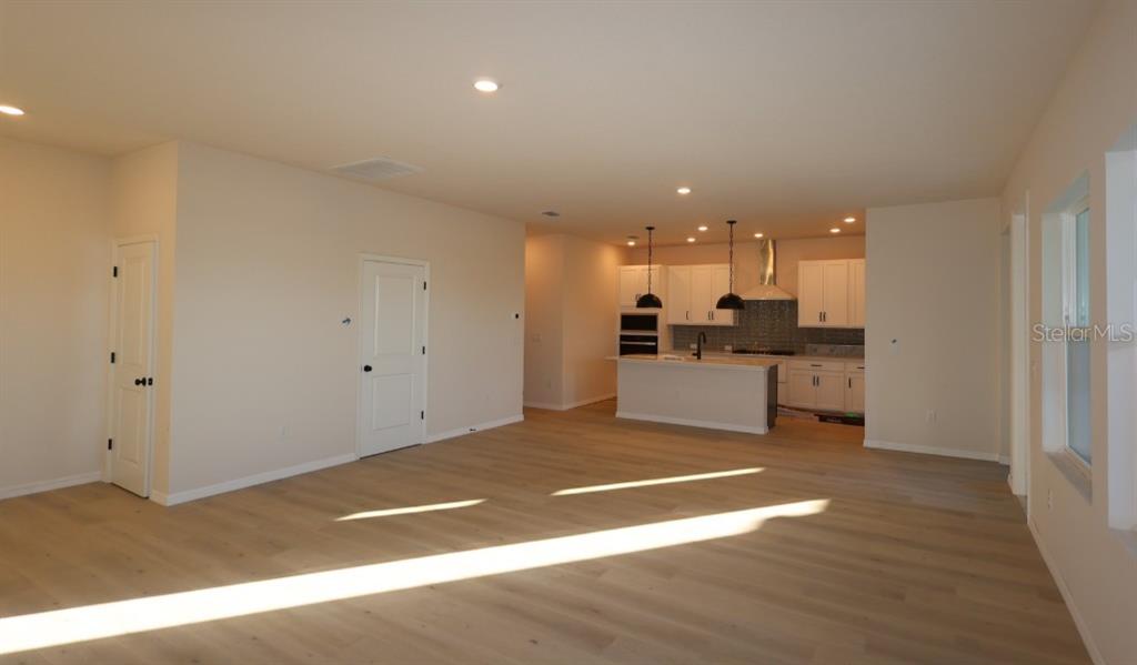 An open-concept living area features light wood flooring, recessed lighting, and a modern kitchen — 5254 COLONY VISTA DRIVE, APOLLO BEACH, FL