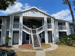 A two-story apartment building features light blue siding, white trim, and an exterior staircase — 718 SUGAR BAY WAY UNIT 202, LAKE MARY, FL