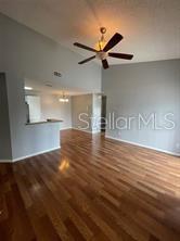 A living room with wood flooring, vaulted ceilings, a ceiling fan, and an open kitchen — 718 SUGAR BAY WAY UNIT 202, LAKE MARY, FL