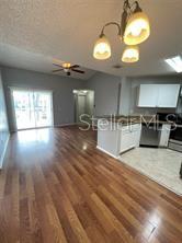 An open-concept living area with wood flooring, a kitchen island, and a sliding glass door — 718 SUGAR BAY WAY UNIT 202, LAKE MARY, FL