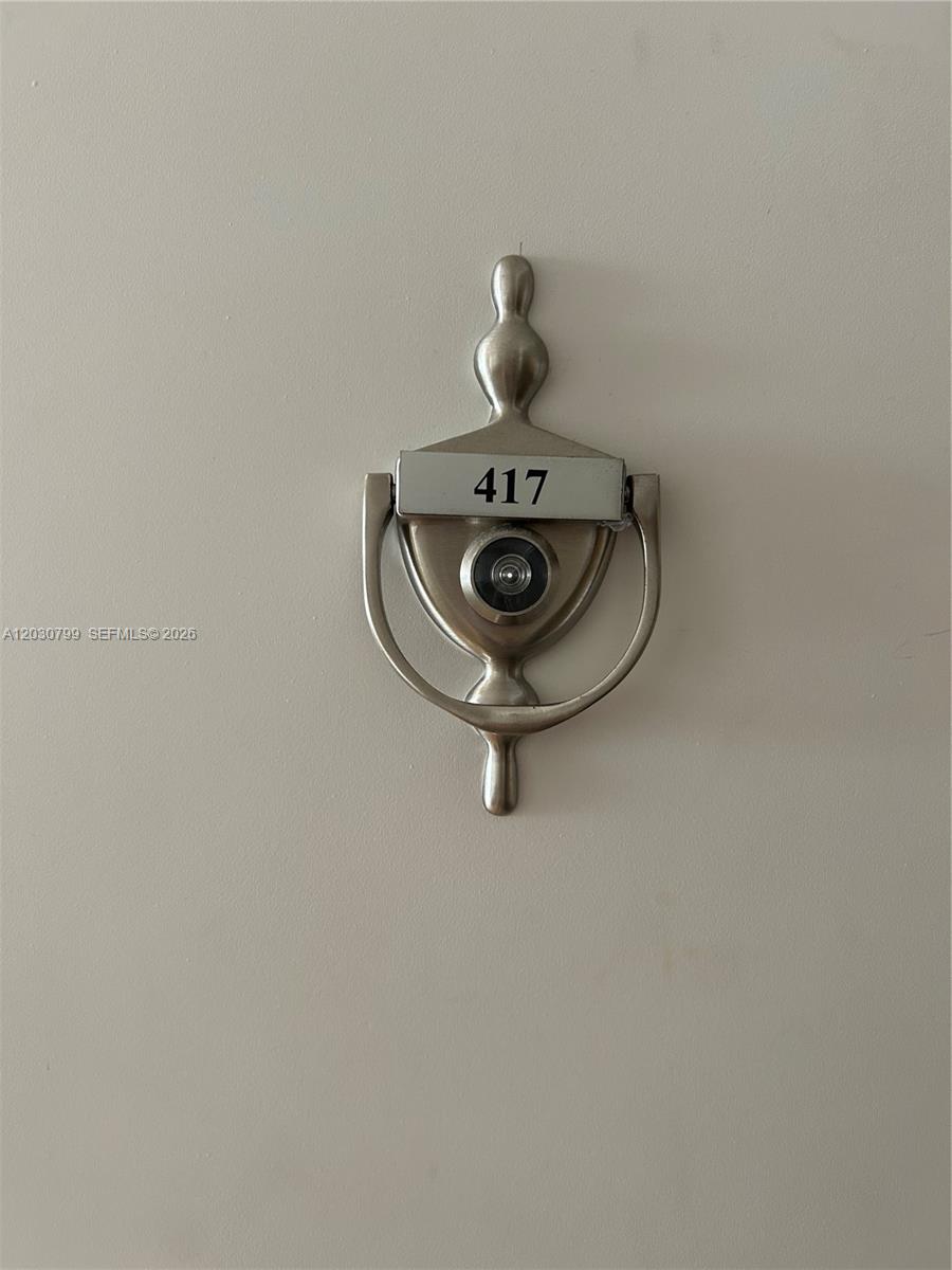 A silver door knocker with an integrated peephole and the number 417 is mounted on a door — 600 NE 36th St # 417, Miami FL 33137, MIAMI, FL