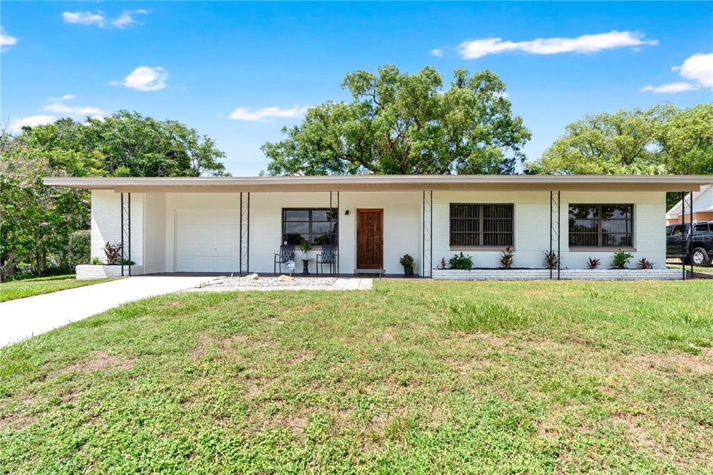 A single-story white brick house with a flat roof, attached garage, and front porch — 5301 BRERETON AVENUE, ORLANDO, FL