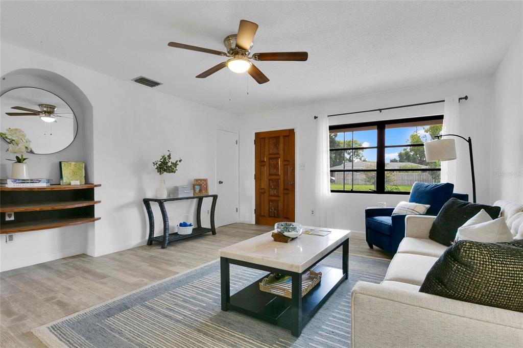 A living room features a ceiling fan, a wooden front door, and a marble coffee table — 5301 BRERETON AVENUE, ORLANDO, FL