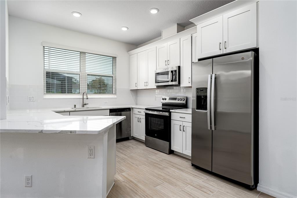 A stainless steel refrigerator stands next to an open door revealing a walk-in pantry — 254 VIA ANINA DRIVE, SARASOTA, FL