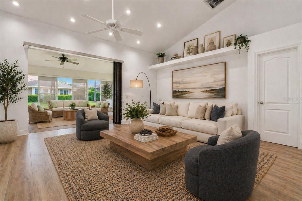 A living room with a vaulted ceiling, white sofa, two dark armchairs, and a patio — 5433 COUNTY ROAD 125, WILDWOOD, FL