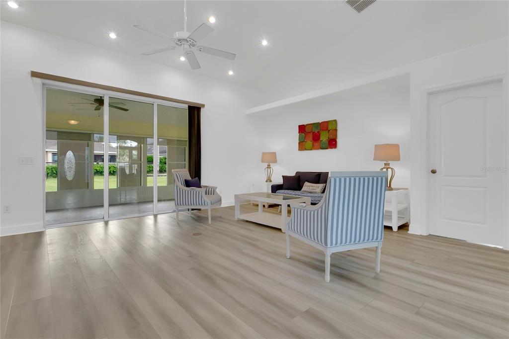 A living room features light wood-look flooring, a ceiling fan, and sliding glass doors — 5433 COUNTY ROAD 125, WILDWOOD, FL