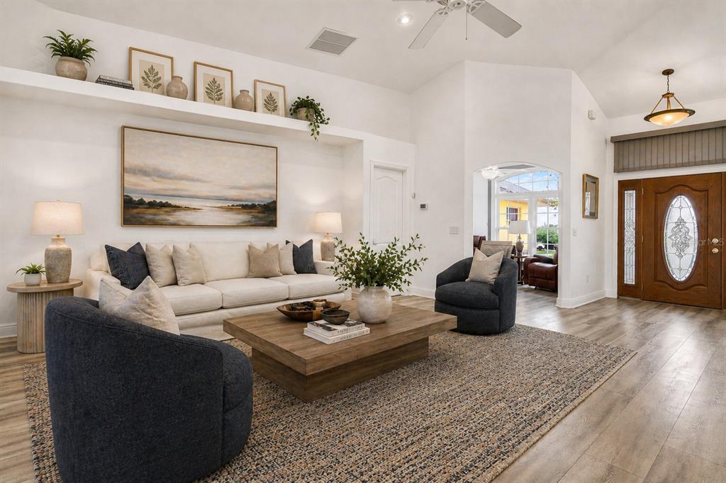A living room features a white sofa, two dark armchairs, a wooden coffee table, and shelving — 5433 COUNTY ROAD 125, WILDWOOD, FL