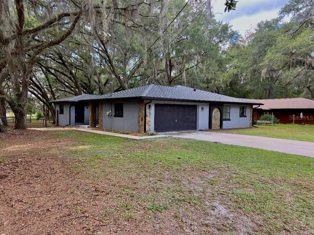 A single-story gray house with a dark roof, stone accents, and a two-car garage — 3512 SW SHOREWOOD DRIVE, DUNNELLON, FL